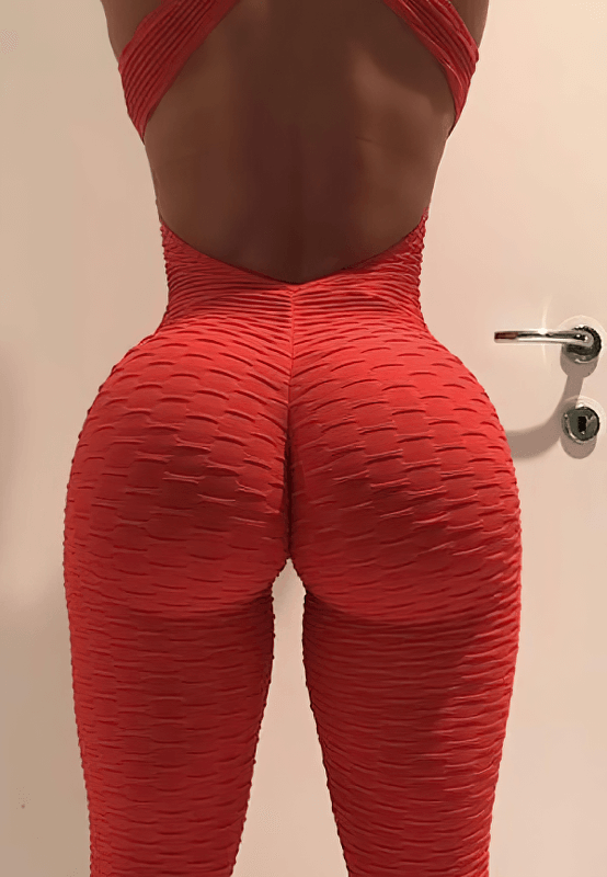 Woman wearing a textured red open-back yoga jumpsuit, showcasing comfortable and breathable fit with anti-wrinkle and quick-dry features.